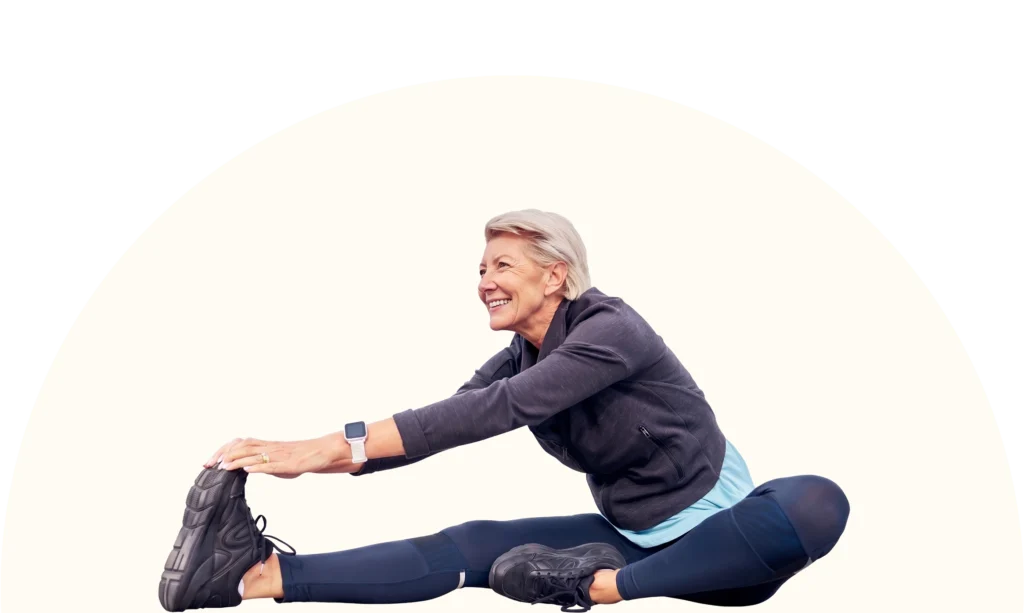 Eine sportliche ältere Frau dehnt ihren Oberkörper.